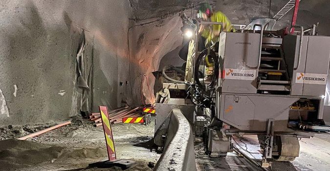 arbeidere støper betongrekkverk i tunell med bistand av maskiner